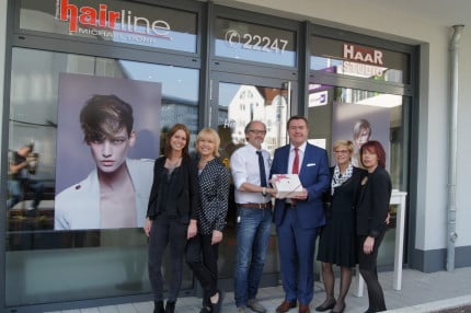 Mit einer Brüder-Grimm-Torte gratulierte OB Claus Kaminsky Friseurmeister Michael Dörr und seinem Team zu Eröffnung des neuen Friseurstudios am Gloria Palais.